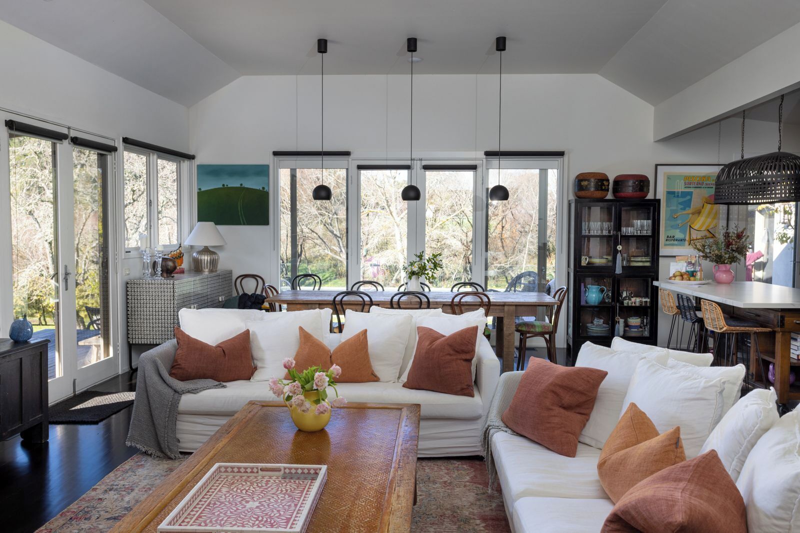 A spacious living area with a large sofa set, a dining table, and a kitchen area with a bar.