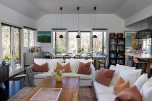 A spacious living area with a large sofa set, a dining table, and a kitchen area with a bar.