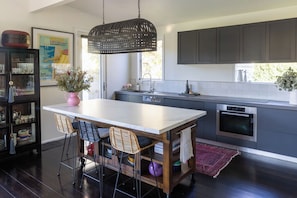 Una cocina moderna con una isla central, muebles oscuros y una lámpara colgante.
