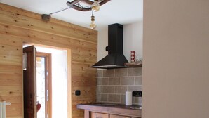 Et træpanelt interiør med et spisebord, stole, et tekøkken og en loftlampe.