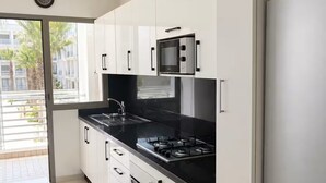 Una cocina moderna con armarios blancos, encimera negra y electrodomésticos de acero inoxidable.