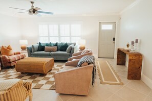A living room with a sofa, armchairs, a coffee table, a floor lamp, a side table, and a ceiling fan. - Sunny Seas - Walk to Beach - Pool (Naples)