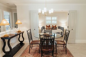 A dining area with a round table, chairs, and a chandelier. - Sunny Seas - Walk to Beach - Pool (Naples)