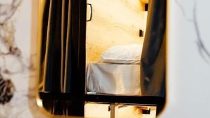 Un espejo que refleja una habitación con cama y mesita de noche.