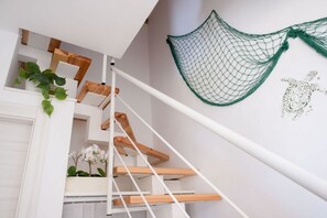 Eine Treppe mit Holzdielen und weißen Geländern, einer grünen Netzdekoration sowie einem Wandbild mit einer Schildkröte.