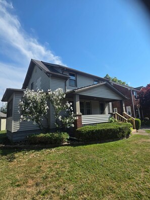 A residential house with a sloped roof, a front porch, and a small front yard. - A Hop ,Skip, and Jump to the Beach (Lorain)
