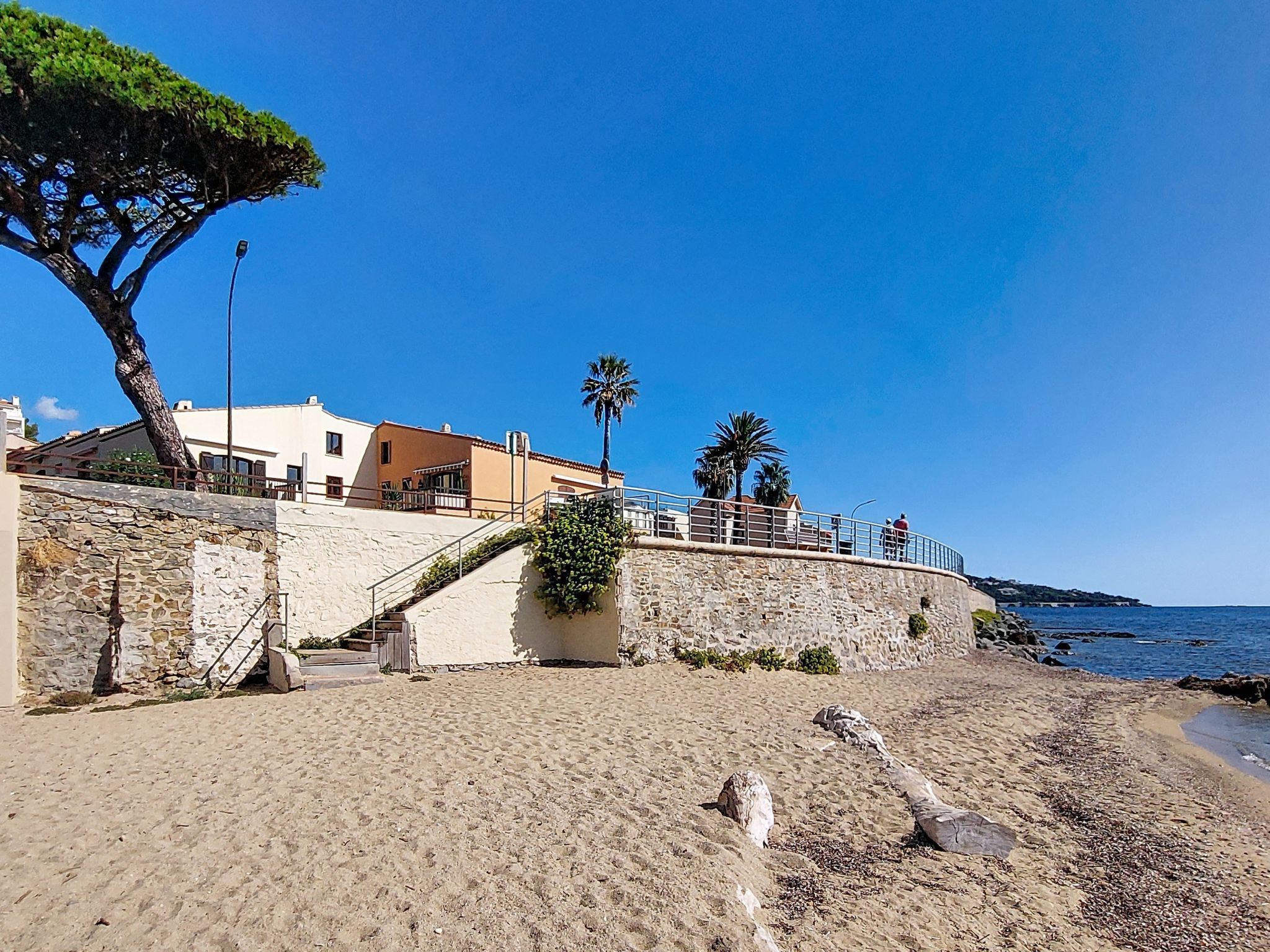 A coastal building with a stone wall, a staircase, and a view of the sea.