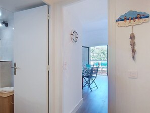 A hallway leading to a dining area with a table and chairs, a wall clock, and a decorative item. - Les Embruns by Interhome (Sainte Maxime)