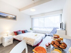 A modern hotel room with a bed, bedside table, lamp, TV, and breakfast setup. - Les Alizés by Interhome (Carnac)