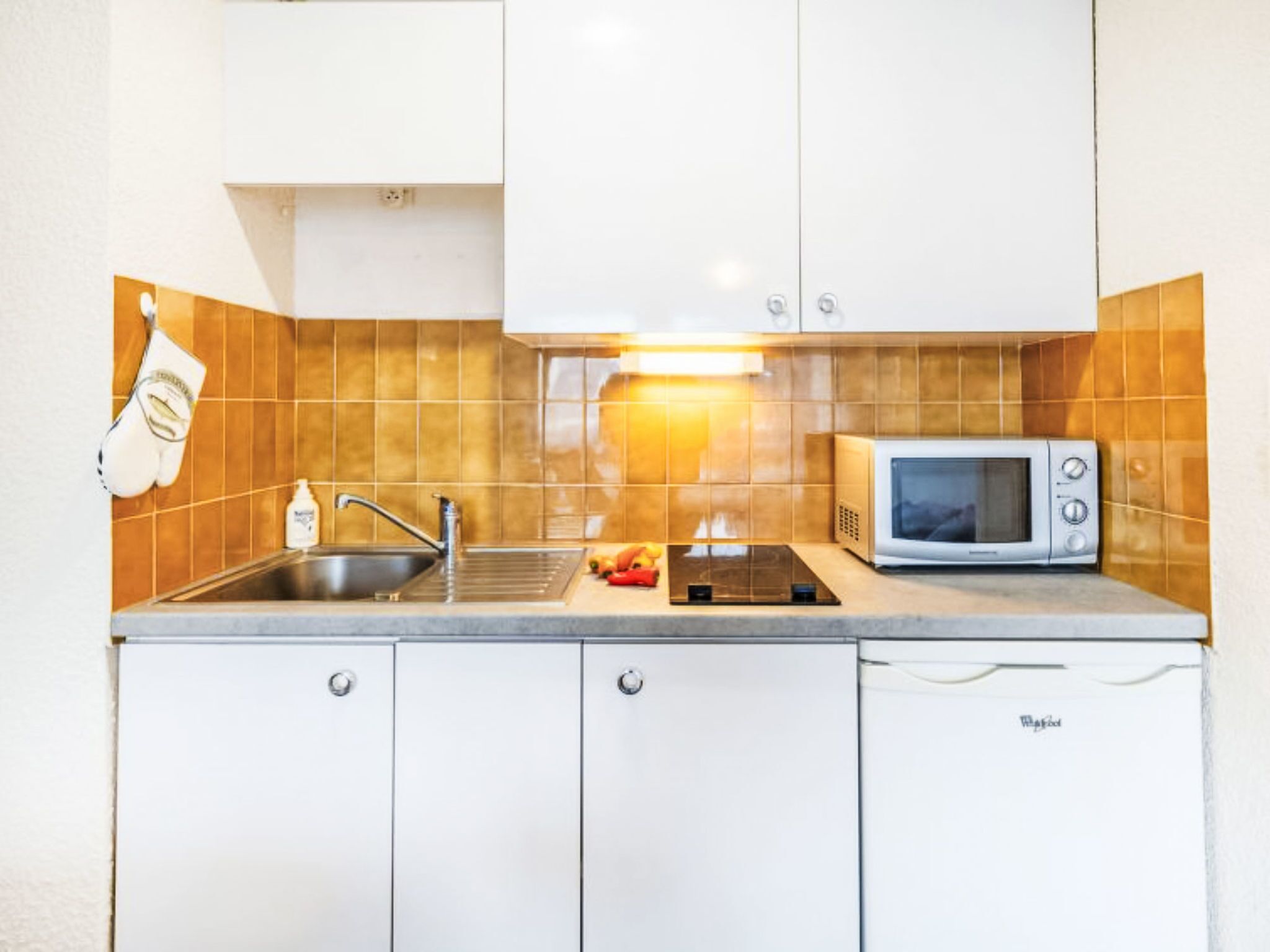 A compact kitchen with a sink, a microwave, and a stove.
