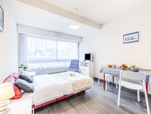 A bedroom with a bed, a desk, a chair, a TV, and a window. - Les Alizés by Interhome (Carnac)