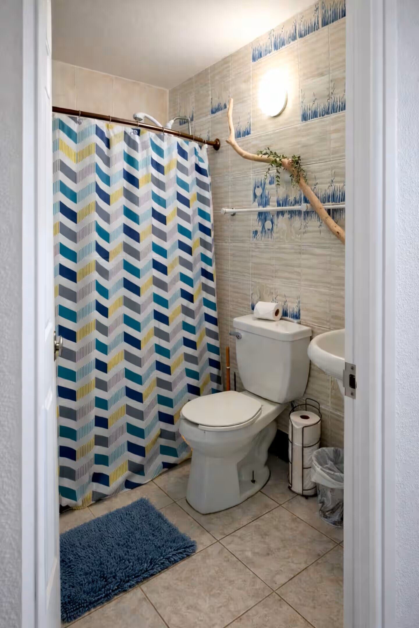 Een badkamer met douchegordijn, toilet, wastafel en betegelde vloer.