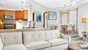 A modern living room with a sofa, dining area, kitchen, and artwork. - Marriott's Desert Springs One Bedroom Villa (Palm Desert)