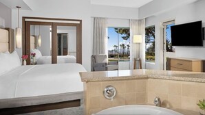 A hotel room with a large bed, a bathroom with a bathtub, a TV, and a view of palm trees. - Marriott's Desert Springs One Bedroom Villa (Palm Desert)