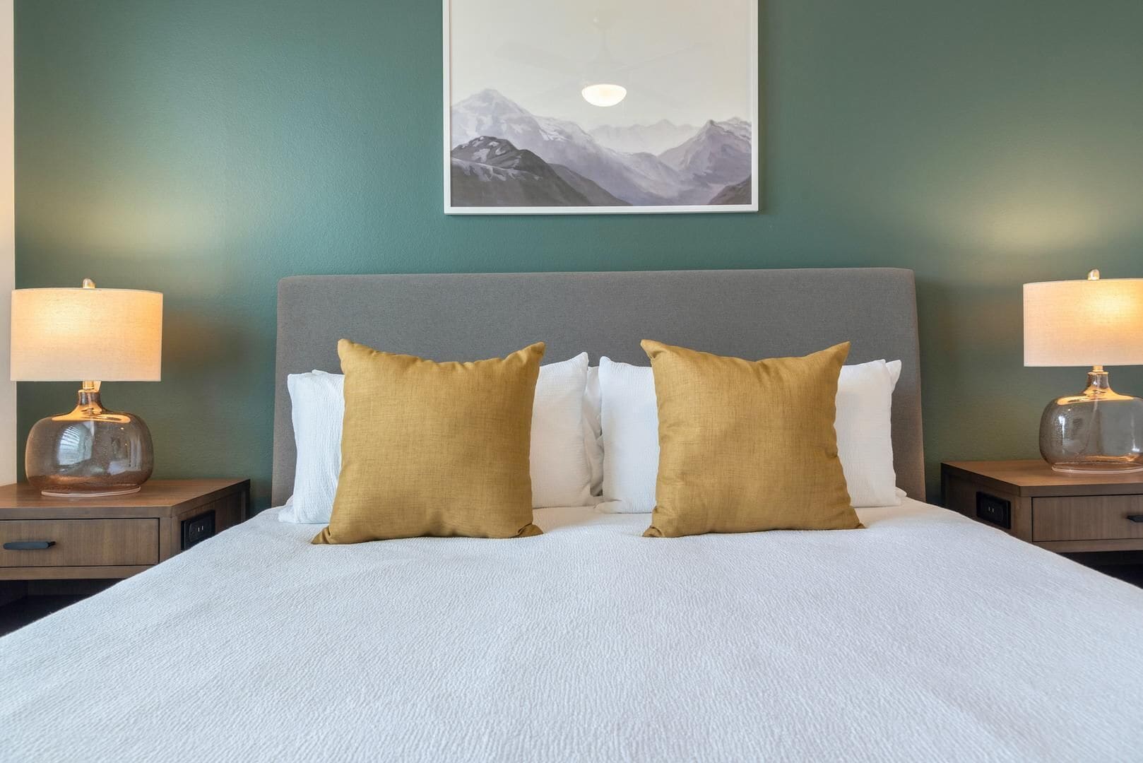 A neatly made bed with two pillows, a headboard, and two bedside lamps.