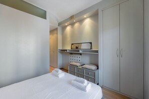 A bedroom with a bed, a wardrobe, a shelf with towels, and a mirror. - Torino Centro | Casa Gran Madre (Torino)
