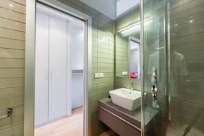 A modern bathroom with a glass shower enclosure, a white sink, and a green-tiled wall. - Torino Centro | Casa Gran Madre (Torino)
