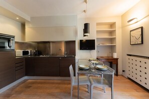 A modern kitchen with a dining area, featuring a microwave, stove, and a flat-screen TV. - Torino Centro | Casa Gran Madre (Torino)