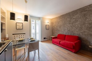 A modern living space with a dining area, a red sofa, and a kitchen. - Torino Centro | Casa Gran Madre (Torino)
