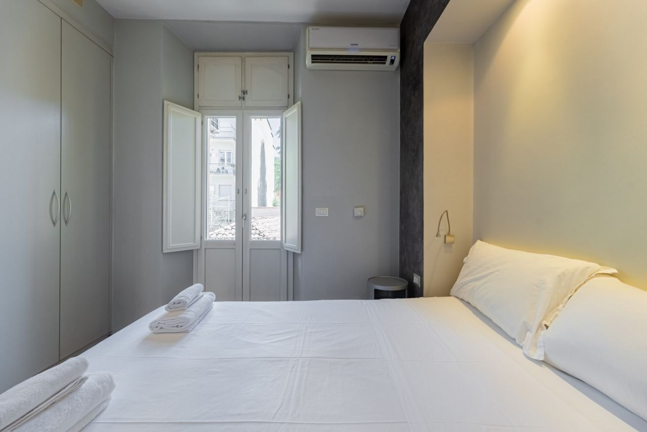 Una habitación de hotel con cama, armario, aire acondicionado y ventana.