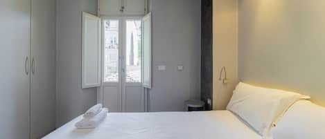 Una habitación de hotel con cama, armario, aire acondicionado y ventana.
