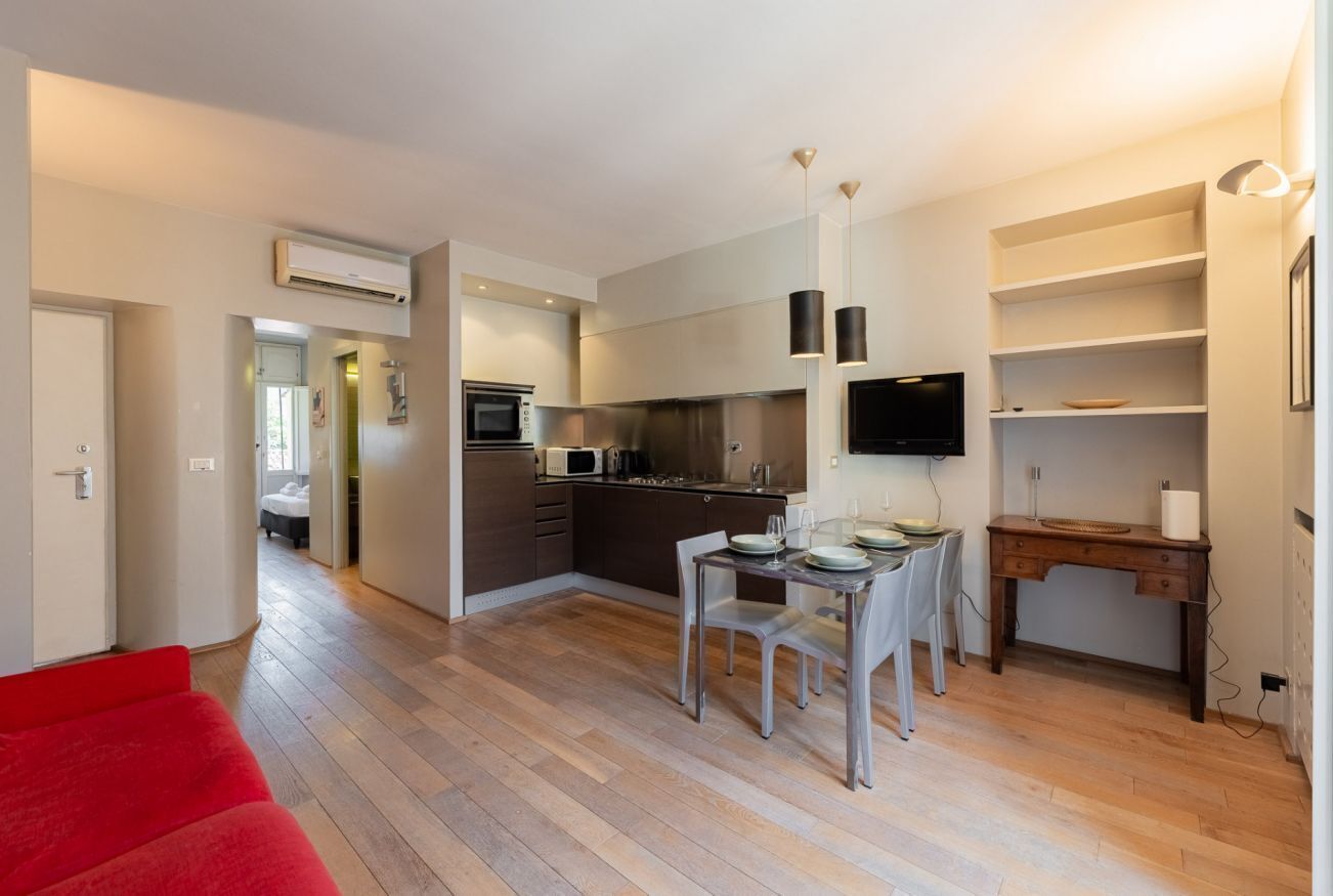 Un apartamento moderno con cocina, comedor y un sofá rojo.