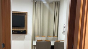 A dining area with a table, chairs, a television, and curtains. - Apartment 15 minutes from Confins International Airport (Lagoa Santa)