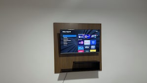 A flat-screen TV mounted on a wall with a wooden panel design. - Apartment 15 minutes from Confins International Airport (Lagoa Santa)