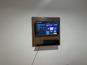 A flat-screen TV mounted on a wall with a wooden panel design. - Apartment 15 minutes from Confins International Airport (Lagoa Santa)