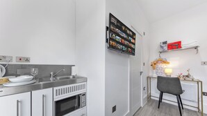 Eine moderne Küche mit Einbauofen, Spüle und einem an der Wand befestigten Flachbildfernseher, der verschiedene Streaming-Dienste anzeigt.