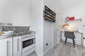 Eine kleine Küche mit integriertem Backofen, einer Mikrowelle und einem Spülbecken.
