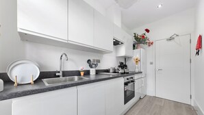 Eine moderne Küche mit weißen Schränken, einer Edelstahlspüle und einem eingebauten Backofen.