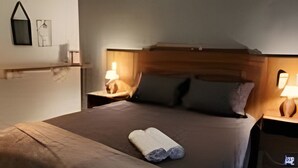 Un dormitorio moderno con una cama grande, mesitas de noche, aire acondicionado de pared y una lámpara de techo.