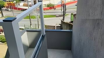 Una escalera conduce a un balcón con vistas a un paisaje urbano, que incluye edificios y una montaña al fondo.