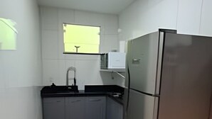A kitchen with a stainless steel refrigerator, a sink, and a window. - Studio RD (Angra dos Reis)