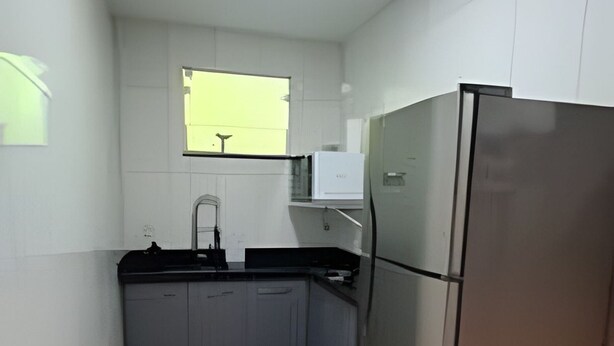 Una cocina con un refrigerador de acero inoxidable, un lavamanos y una ventana.