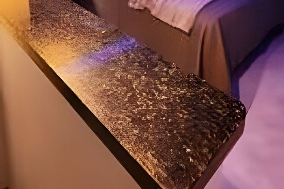 Una habitación de hotel con cama, mesita de noche y dos lámparas colgantes.