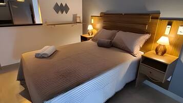 Un lit bien fait, avec une couverture, deux tables de chevet avec des lampes et un luminaire fixé au mur.