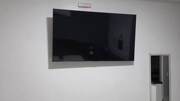 Une pièce équipée d’un téléviseur à écran plat fixé au mur, d’une porte et d’un interrupteur sur le mur.
