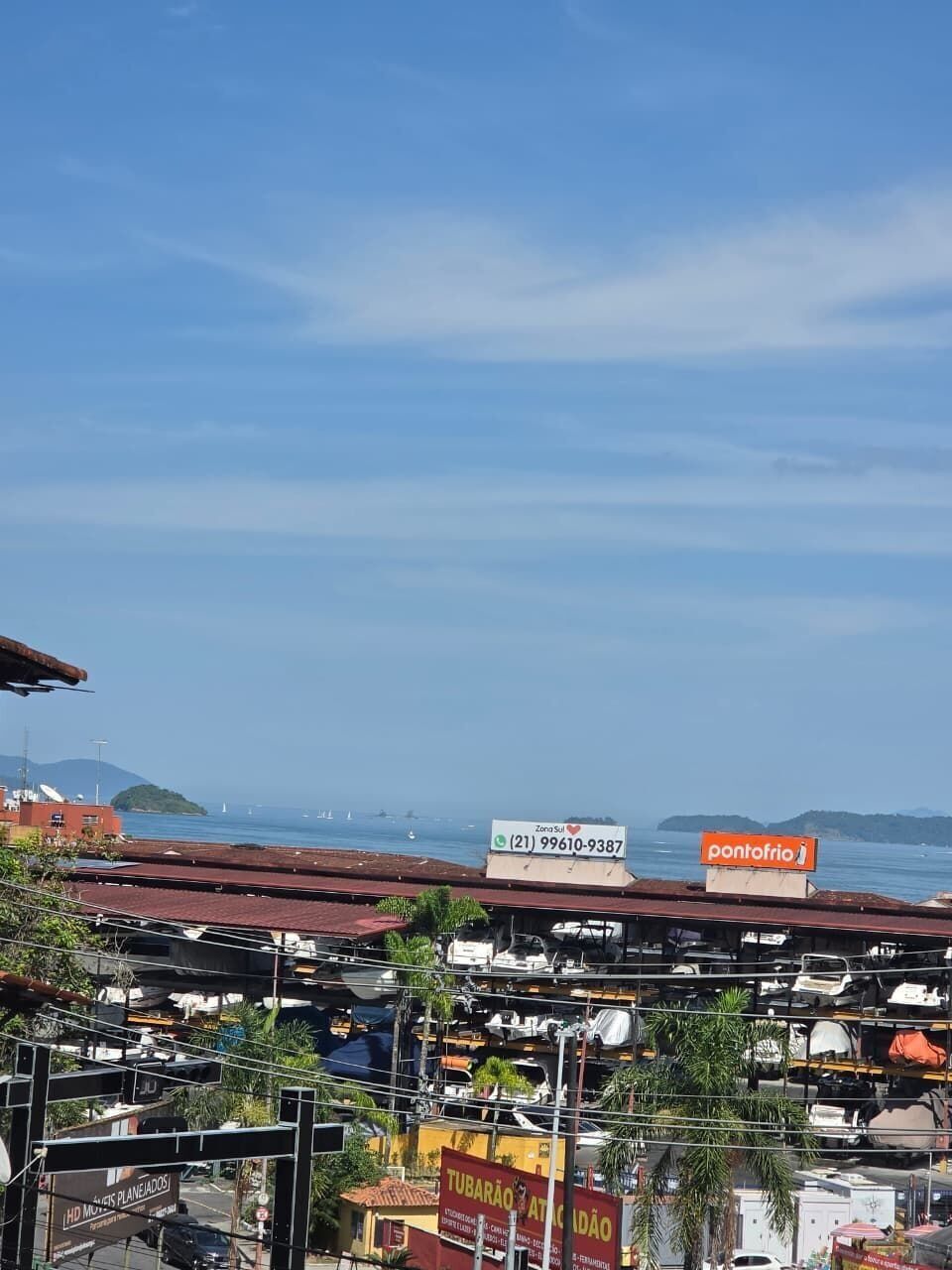 A coastal view with a marina, a building with a sign for 'ZonaSul', and a 'pontefrio' sign.
