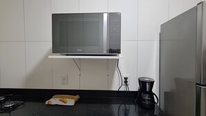Una cocina con microondas, cafetera y tostadora sobre la encimera.