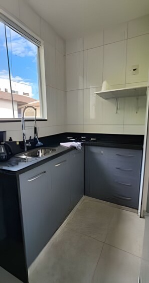 Egy modern konyha, ablakkal, mosogatóval és szekrényekkel.