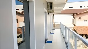 A corridor with a glass door, a blue mat, and a metal railing. - Studio RD (Angra dos Reis)