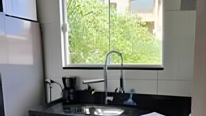 A kitchen with a window, a sink, a refrigerator, and cabinets. - Studio RD (Angra dos Reis)