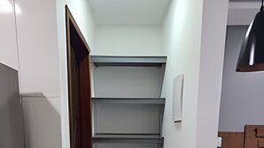 Una cocina estrecha con un mueble estantería empotrado, un refrigerador y una encimera.