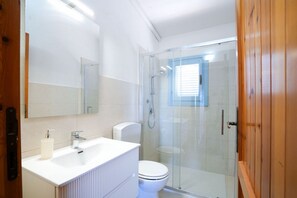 Ein modernes Badezimmer mit Waschbecken, Toilette und einer Duschkabine aus Glas.