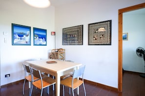 Ein Essbereich mit Tisch und Stühlen, einem Korbwannen und drei gerahmten Kunstwerken an der Wand.