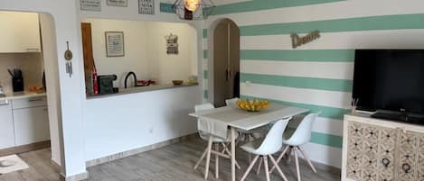 Cocina moderna con comedor, televisor y pared a rayas.