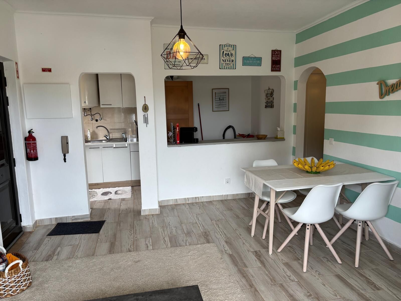 A compact kitchen with white cabinets, a dining area with a table and chairs, and a striped wall.