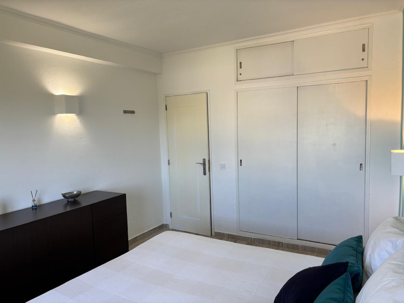 Een slaapkamer met een bed, een dressoir en een garderobe.